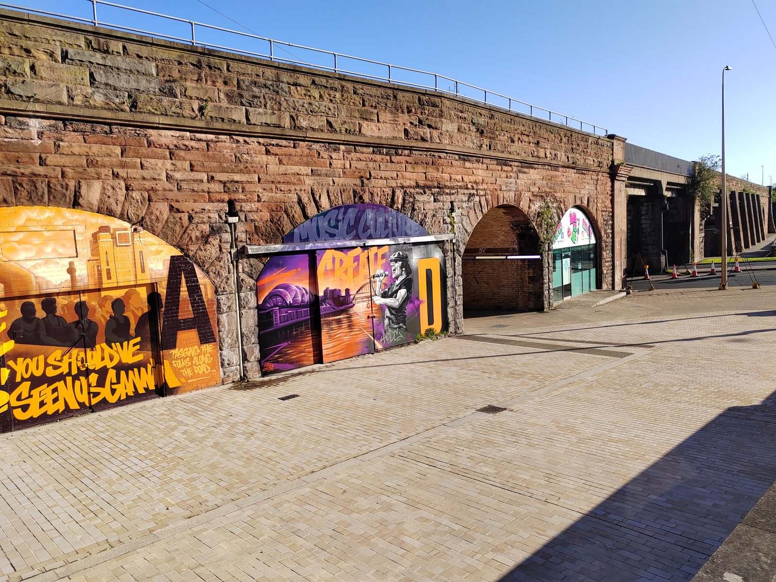 East end of the Askew Road arches showing the large open through-arch and gold and purple murals on adjacent arches.