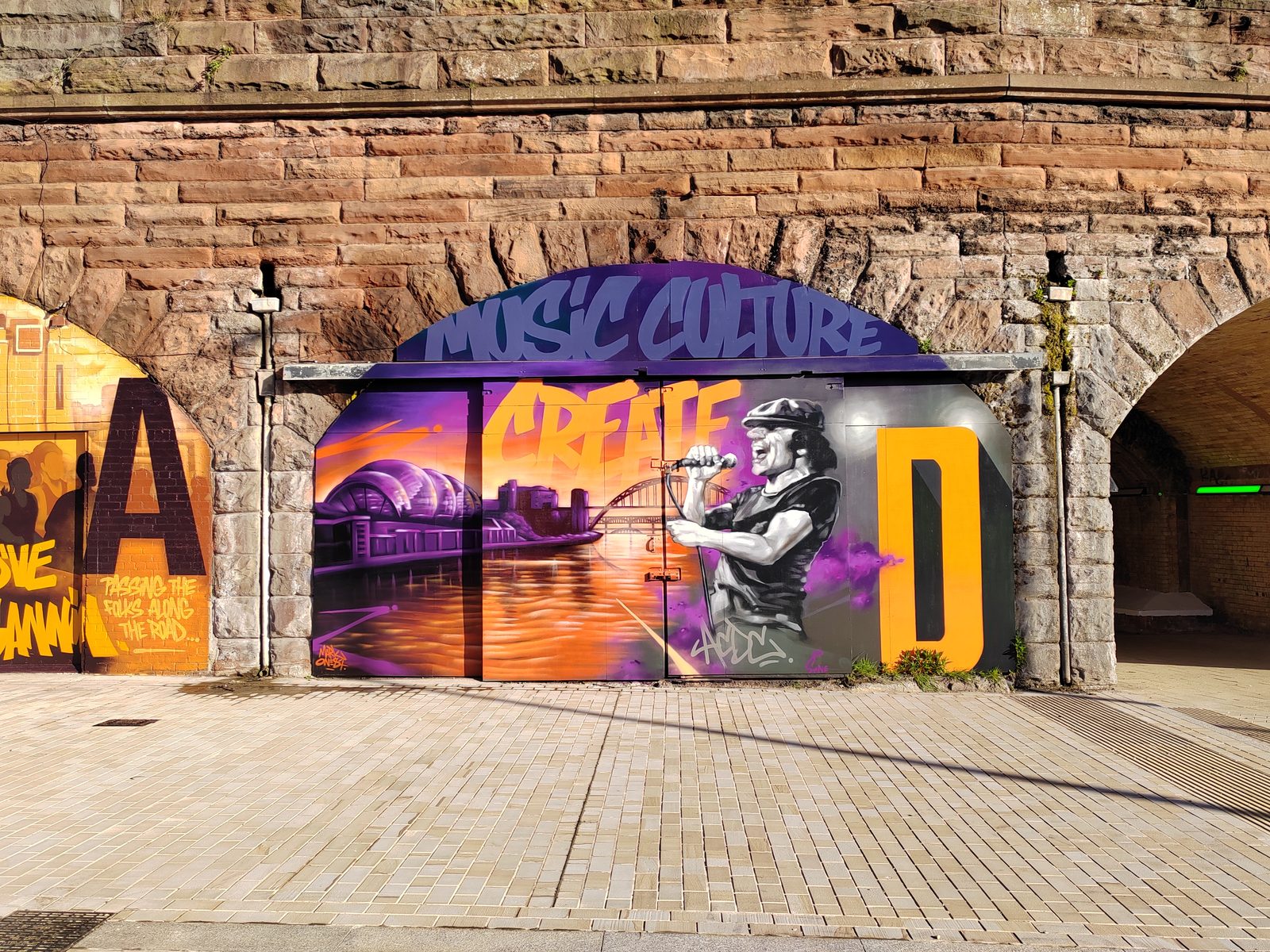 Close-up of a single railway arch with a large purple and orange mural reading Music Culture Create, showing the scale and character of the arch openings.